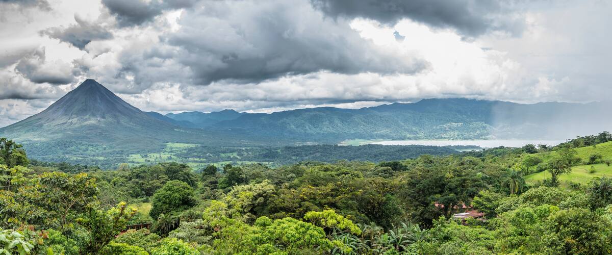 A lush green landscape with a prominent mountain in the background and a body of water in the distance.