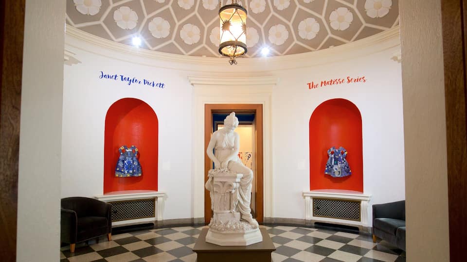 A gallery with a checkered floor, red walls, and a central statue.