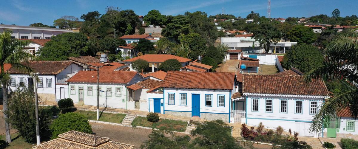 A cluster of white and blue houses with red roofs, surrounded by greenery and a clear blue sky.