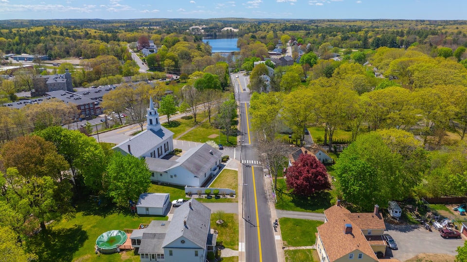 A town with a prominent church, a lake, and surrounding greenery.