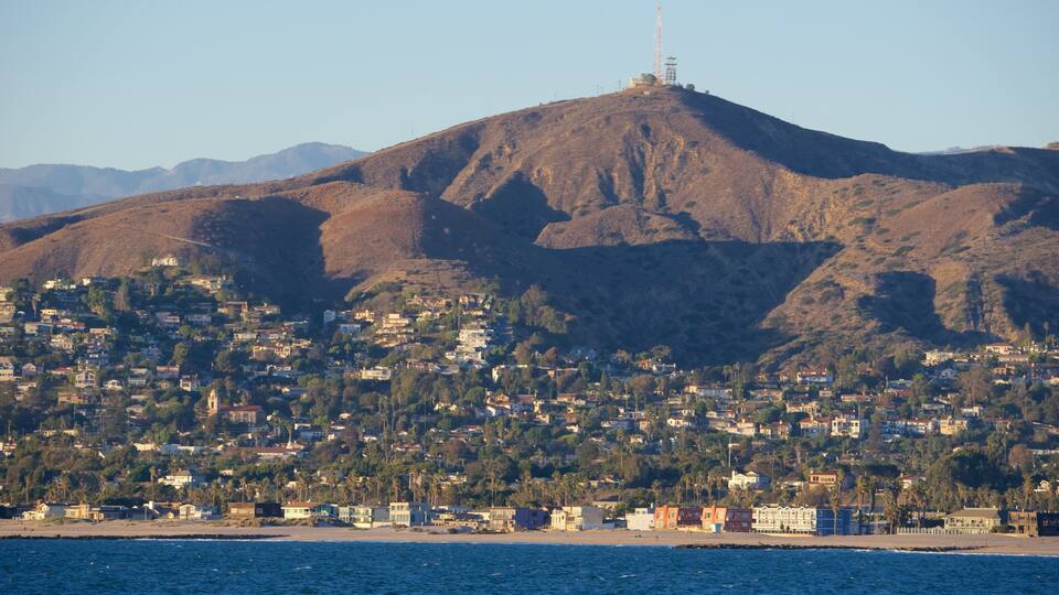 A coastal cityscape with a prominent hill and a tall tower on top.