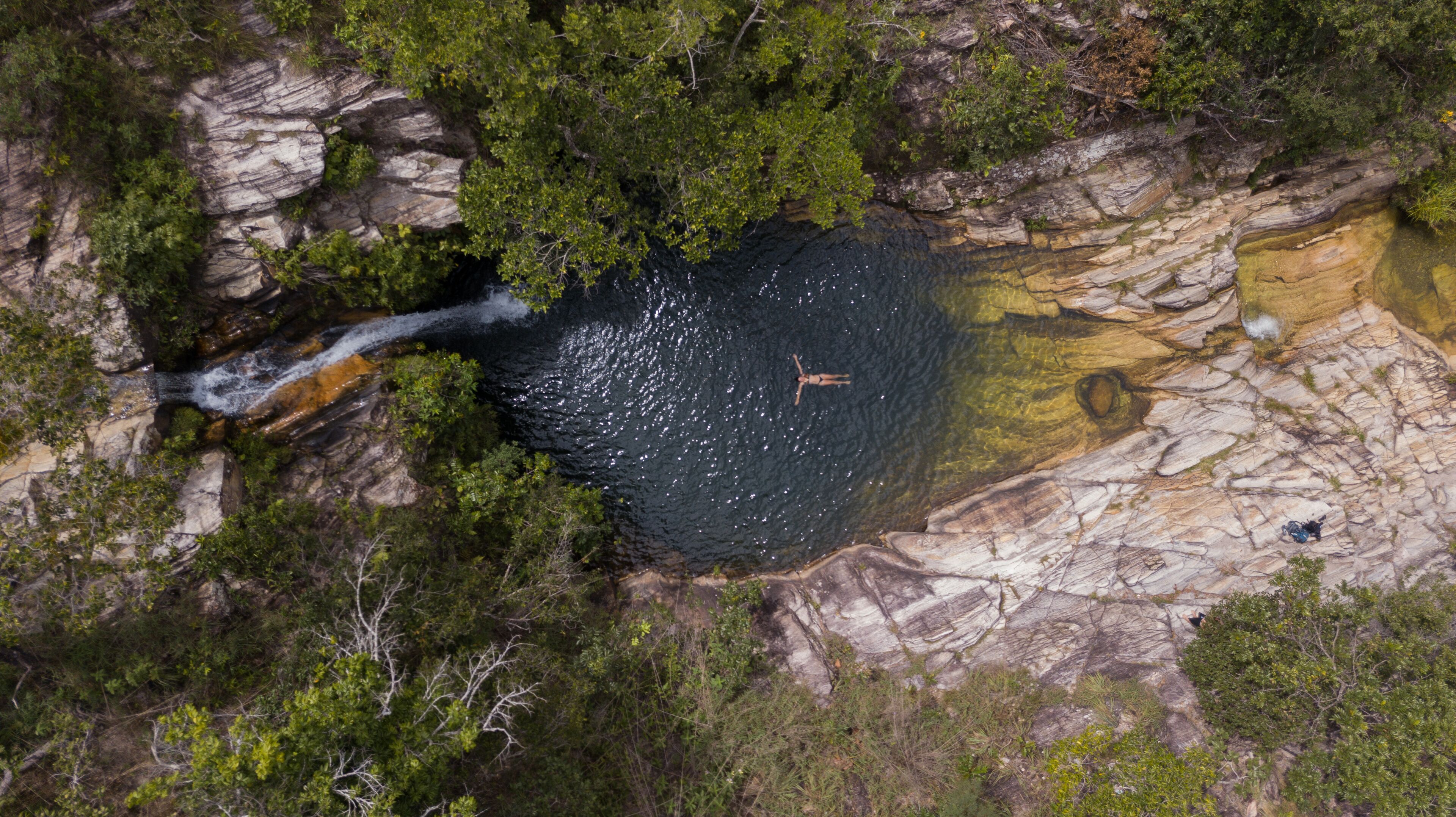 A waterfall cascading into a rocky pool surrounded by dense greenery.