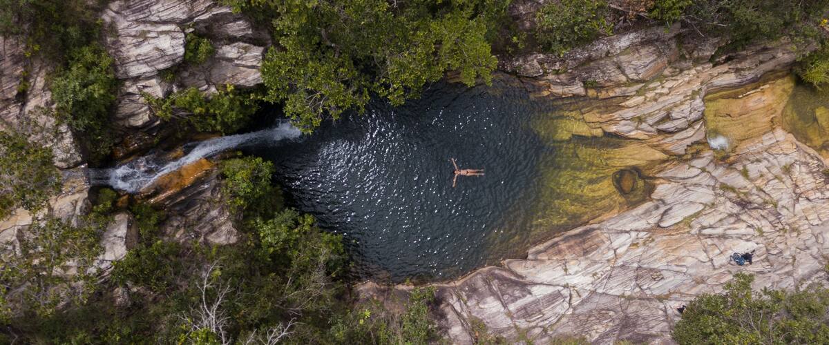 A waterfall cascading into a rocky pool surrounded by dense greenery.