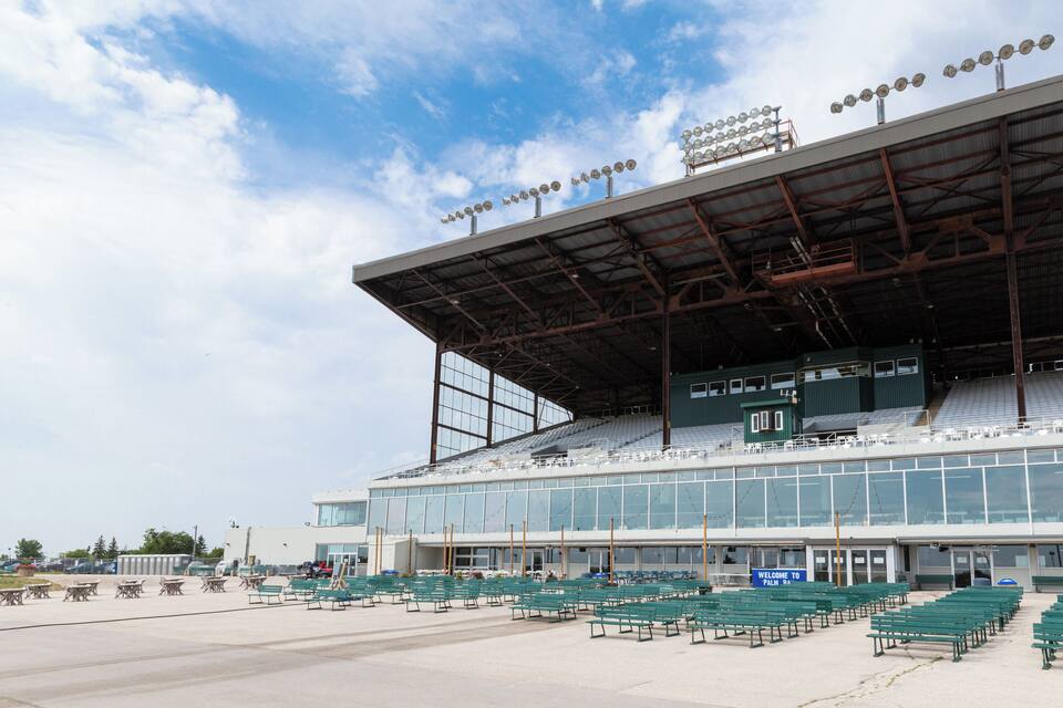 A large stadium with green seating and a covered upper level.