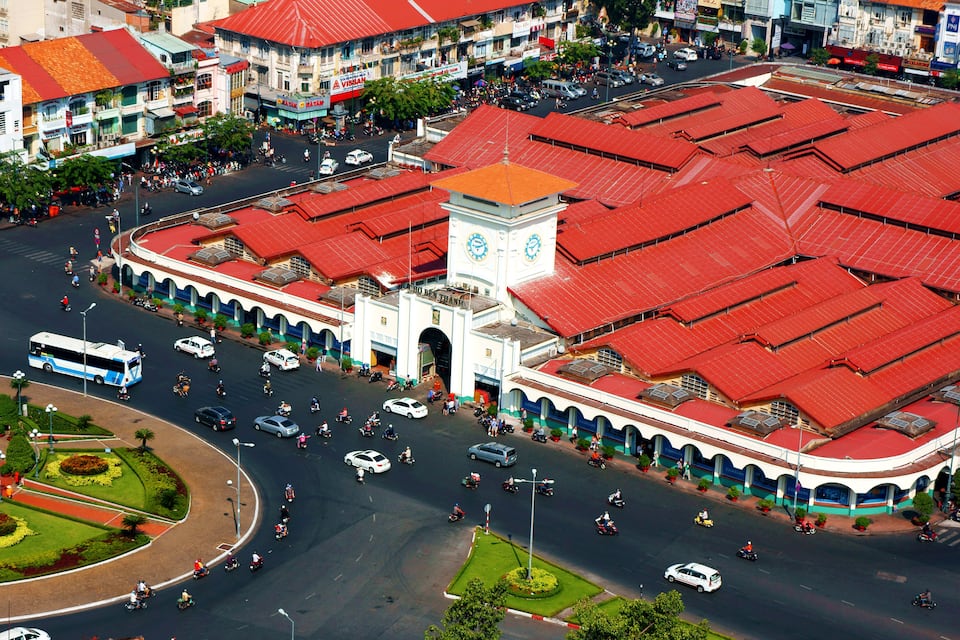 An aerial view of a city with a large building with a clock tower, surrounded by roads and vehicles.