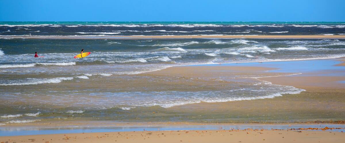 A beach with waves and a clear blue sky.