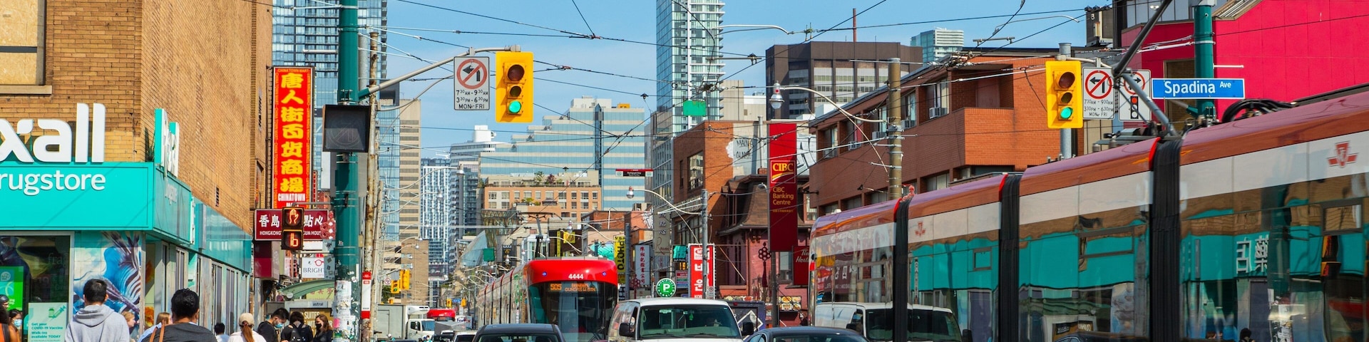 Una calle urbana concurrida con vías de tranvía, coches y peatones.