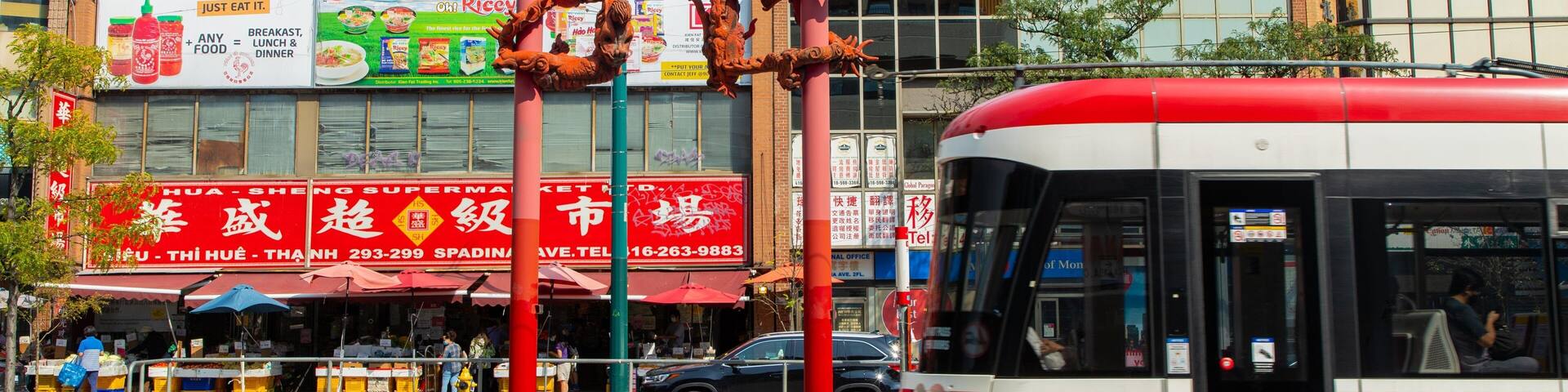 A street with a red bus, a supermarket, and a building with Chinese characters.