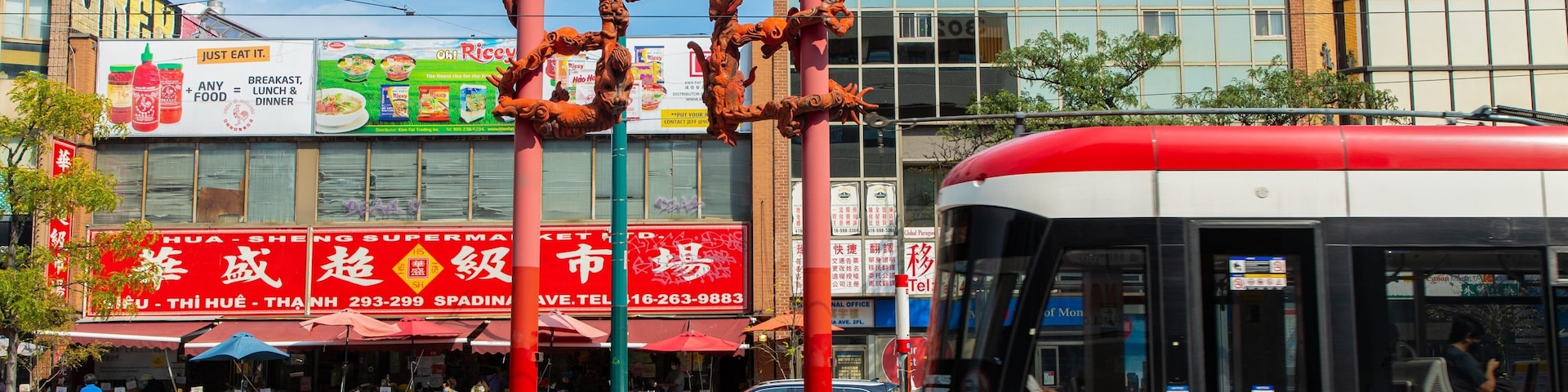 Una calle con un autobús rojo, un supermercado y un edificio con caracteres chinos.