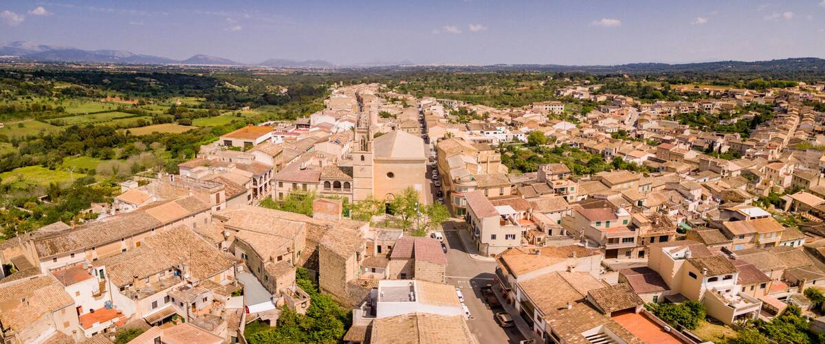 A historic town with a prominent church, terraced houses, and rolling hills in the background.