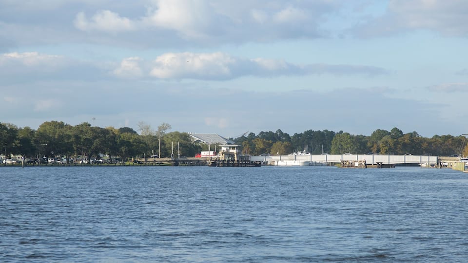A waterfront with a dock, a bridge, and a boat.