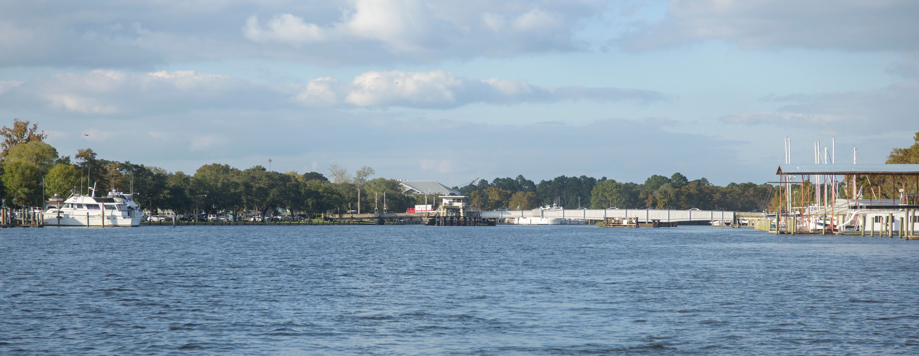 A waterfront with a dock, a bridge, and a boat.
