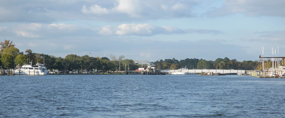 A waterfront with a dock, a bridge, and a boat.