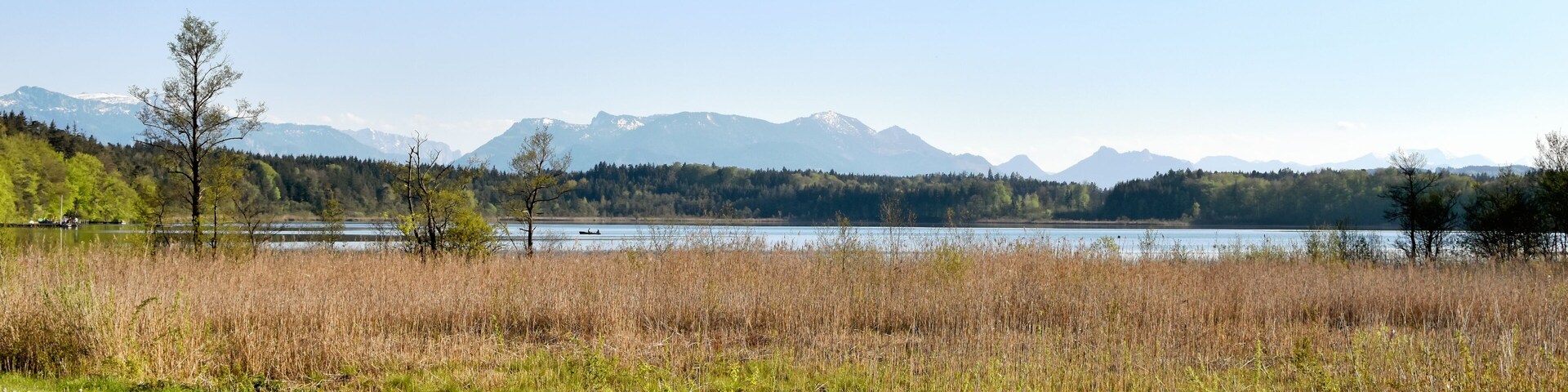 A grassy field with a lake and mountains in the background.