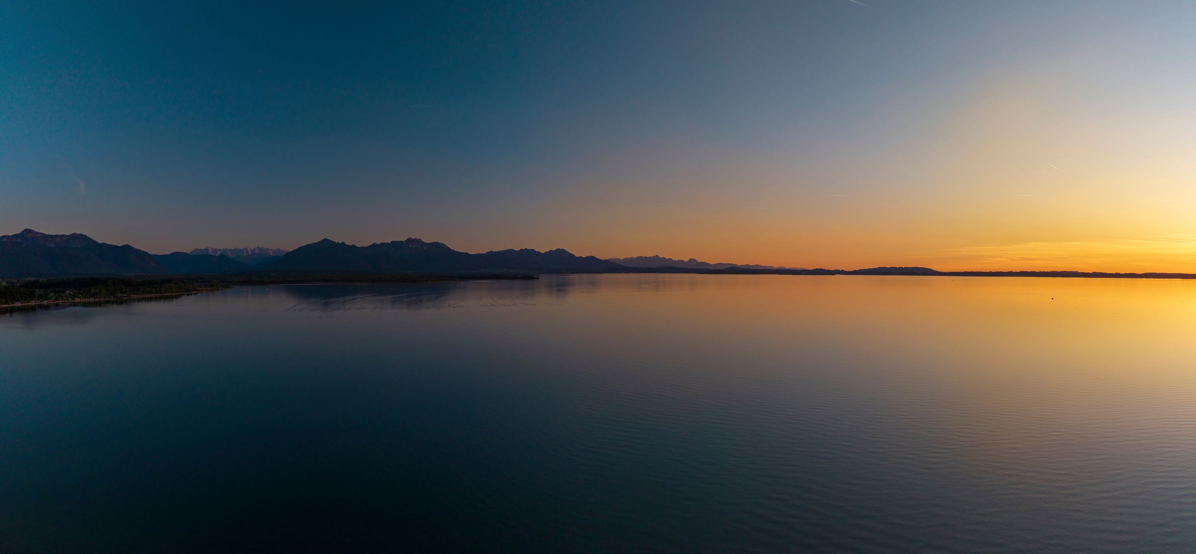 Un lac paisible qui reflète les montagnes et un ciel au coucher du soleil.