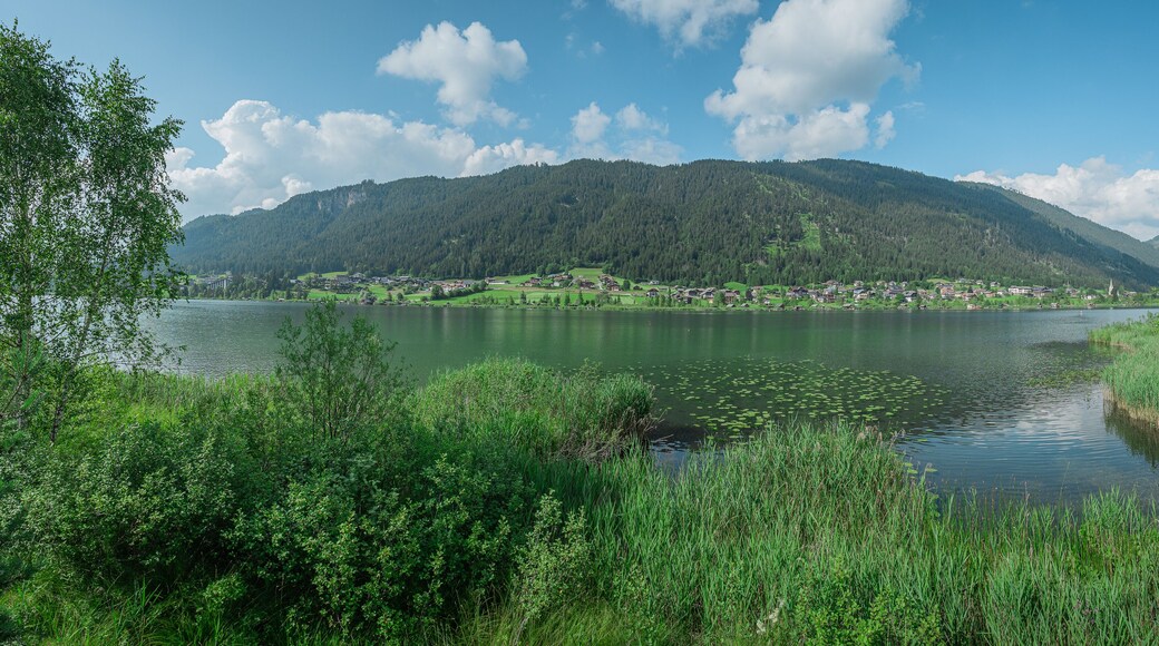 Wide panorama of weisensee in austria, visible church and typical village houses on the banks of picturesque alpine lake. one of austria's top destinations