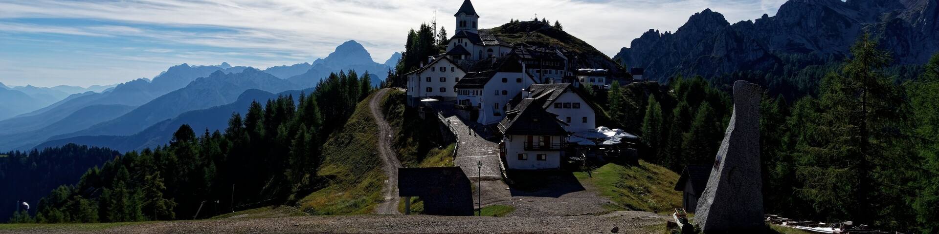 A mountain village with white houses, a church, and a stone monument.