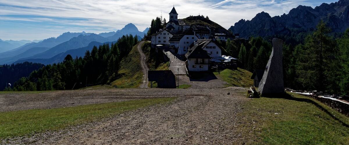 A mountain village with white houses, a church, and a stone monument.