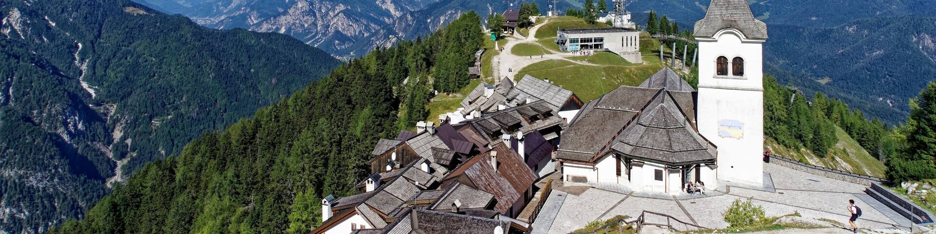 A mountain village with traditional houses, a church, and a bell tower.