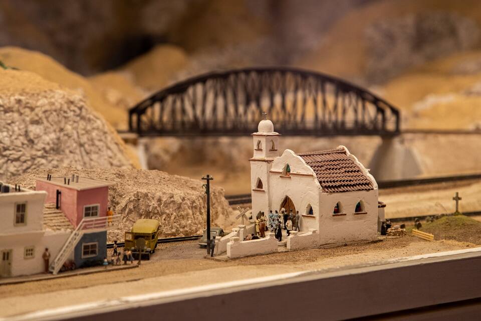 Modelo detallado de un pueblo con una iglesia, vías de tren y un puente.