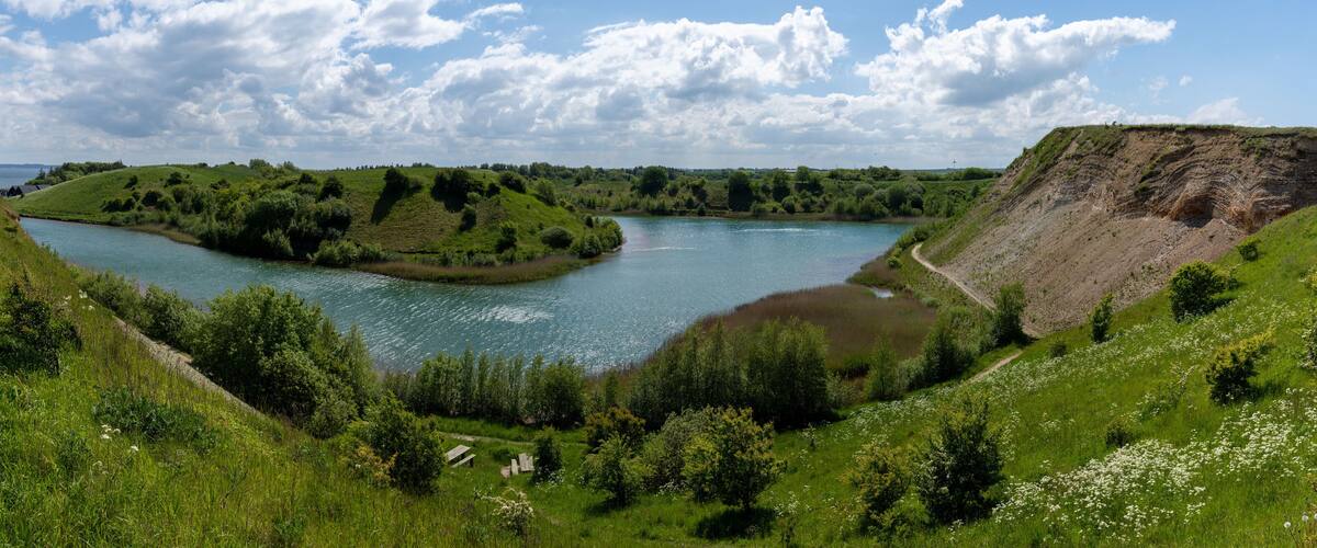 A river winding through lush green hills with a steep cliff on one side and a small island in the middle.