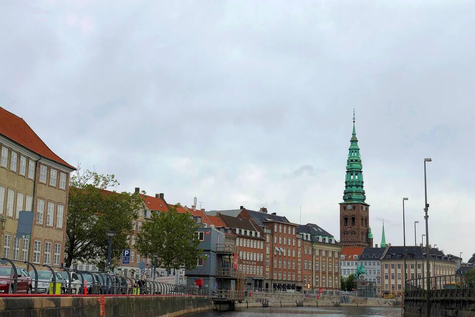 A canal with buildings and a green spire in the background.