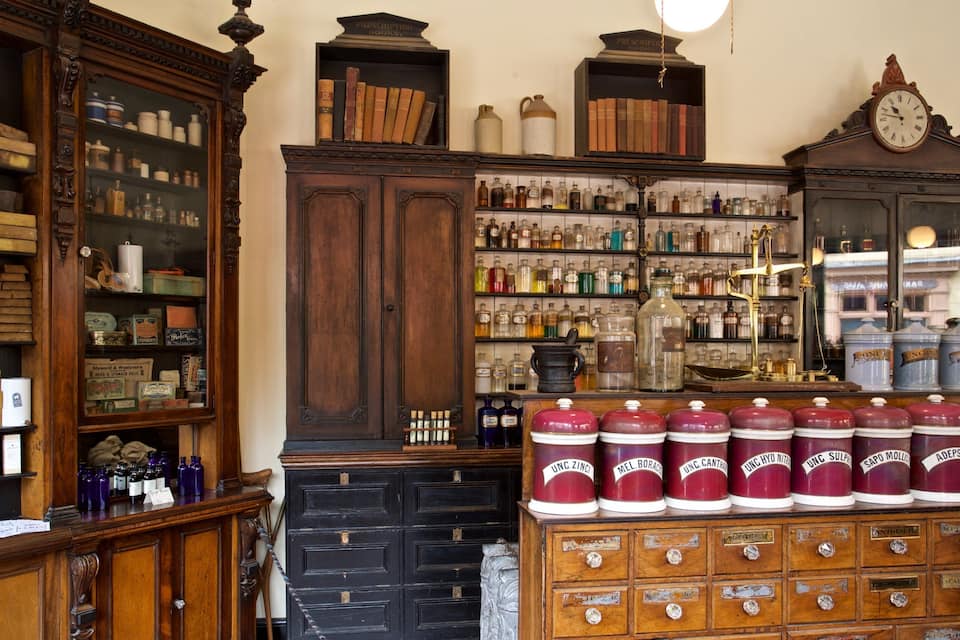 A vintage apothecary with wooden cabinets, glass jars, and antique books.