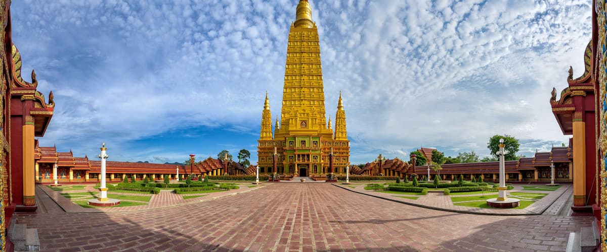 A large, golden temple complex with a central tower, surrounded by manicured gardens and traditional architecture.