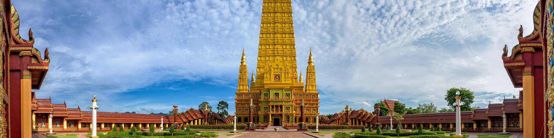 A large, golden temple complex with a central tower, surrounded by manicured gardens and traditional architecture.
