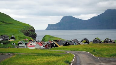 The village of Gjogv sits right on the coast of Eysturoy, with a small gorge nearby and imposing flat-topped mountains in the distance.