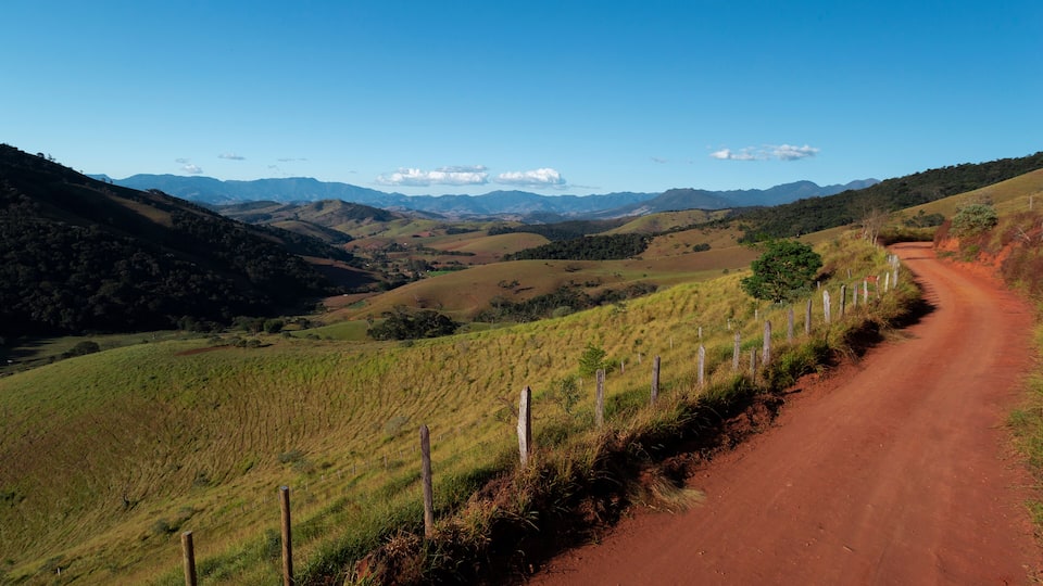A dirt road winding through a hilly landscape with a clear blue sky.