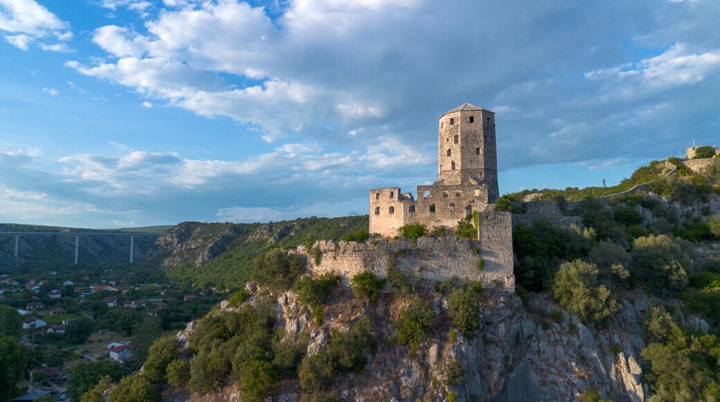 Un château de pierre historique, perché sur une colline, avec un pont en arrière-plan.