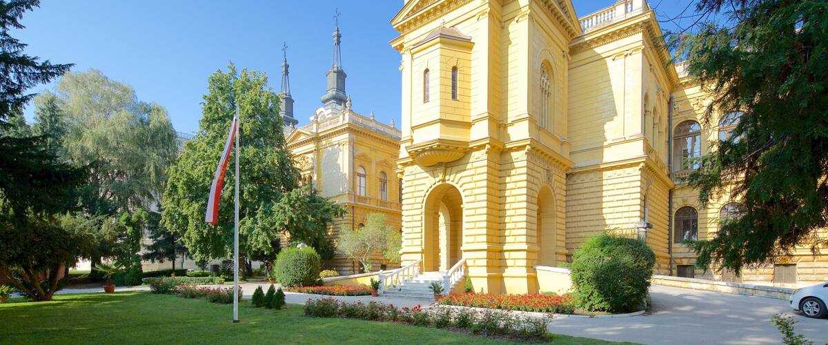 A yellow church with a dome and a bell tower, surrounded by trees and a flag.
