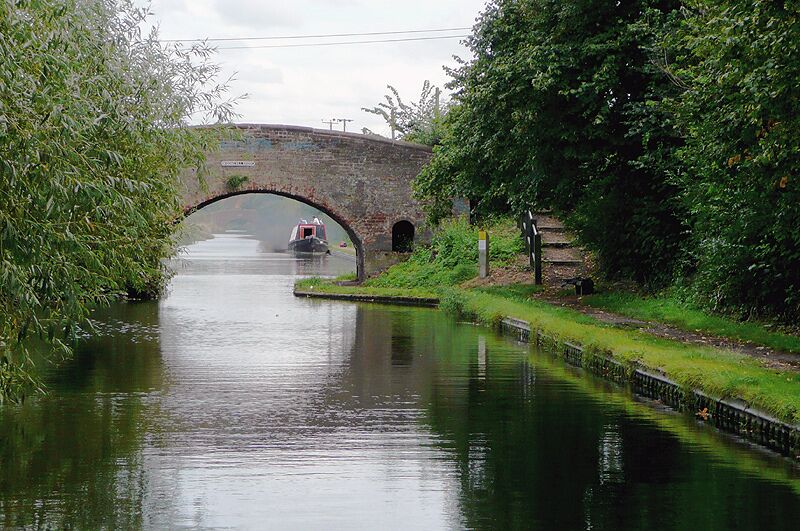 Wiggins Hill Bridge near Curdworth, Warwickshire Birmingham and Fazeley Canal. The original purpose of this canal was to provide a link between Birmingham and the south east of England, by way of the Coventry Canal and the Oxford Canal. John Smeaton was the engineer, and the canal was completed in 1789. The moored narrowboat beyond the bridge is having engine problems, and has just blown out an almighty cloud of murky smoke! The bridge carries Wiggins Hill Road from the A4097 (to the right) to Over Green and Grove End.