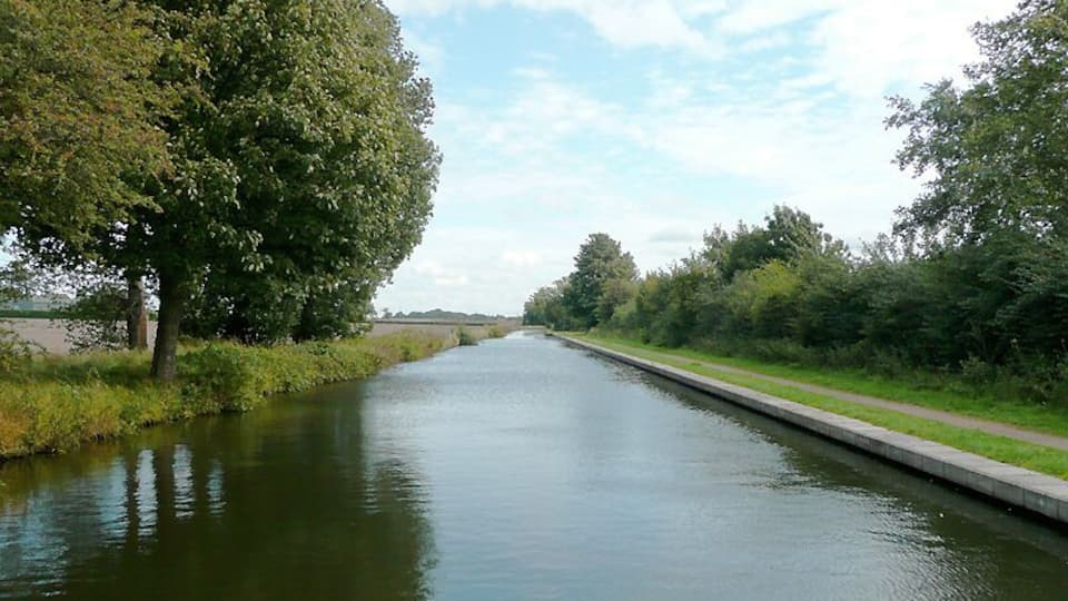 Birmingham and Fazeley Canal near Minworth, Birmingham Here the canal is leaving the built up part of Birmingham and approaches Curdworth through flat farm land. There are still some recently built factory units and a sewage works to the south (right) of the canal. The original purpose of this canal was to provide a link between Birmingham and the south east of England, by way of the Coventry Canal and the Oxford Canal. John Smeaton was the engineer, and the canal was completed in 1789. The canal now runs from the BCN Main Line at Old Turn Junction, Birmingham to the Coventry Canal at Fazeley Junction, just outside Tamworth. The length is 15 miles (24 km), and it includes 38 locks. There is also a short branch to Digbeth, Birmingham. Information from Wiki Birmingham_and_Fazeley_Canal .