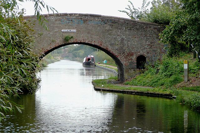 Wiggins Hill Bridge near Curdworth, Warwickshire Birmingham and Fazeley Canal. The original purpose of this canal was to provide a link between Birmingham and the south east of England, by way of the Coventry Canal and the Oxford Canal. John Smeaton was the engineer, and the canal was completed in 1789. The bridge carries Wiggins Hill Road from the A4097 (which is to the right) to Over Green and Grove End.