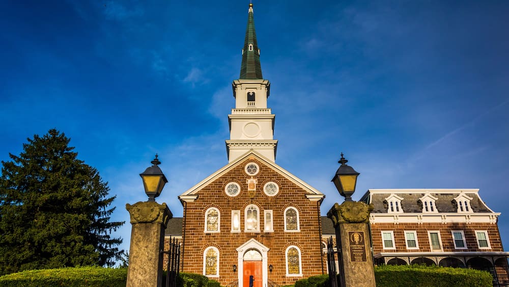 A church with a tall steeple, a large wooden door, and a clock tower.