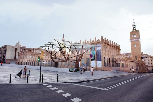 Ein historisches Gebäude mit einem Turm, einer großen Metallskulptur und einer Fußgängerampel.
