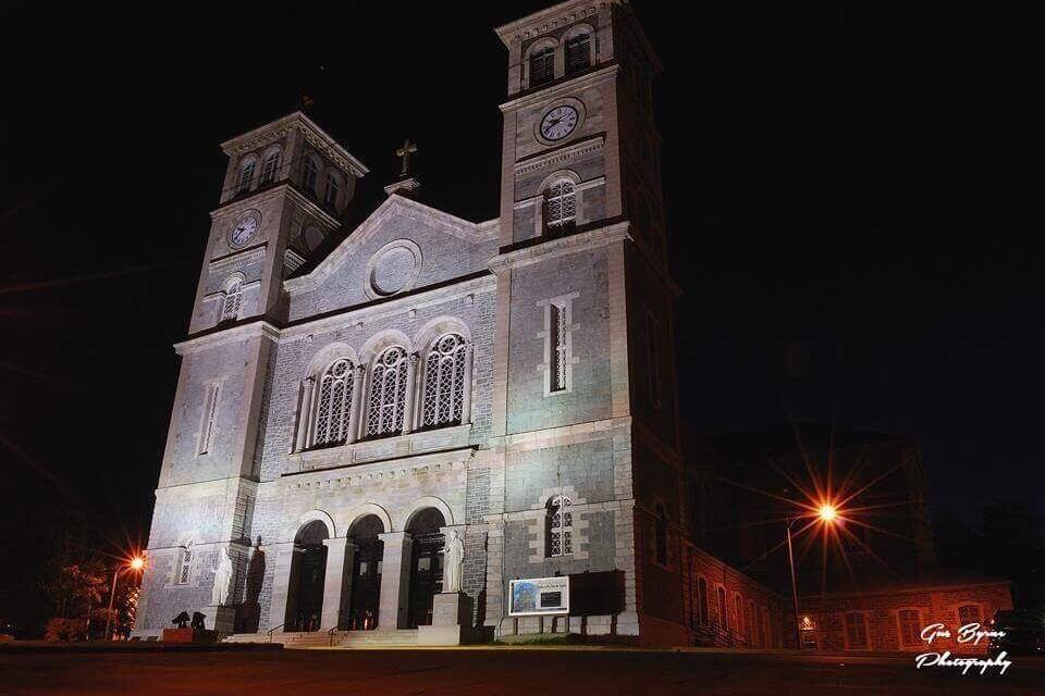 Une grande église illuminée, dotée de deux tours et d’une horloge.