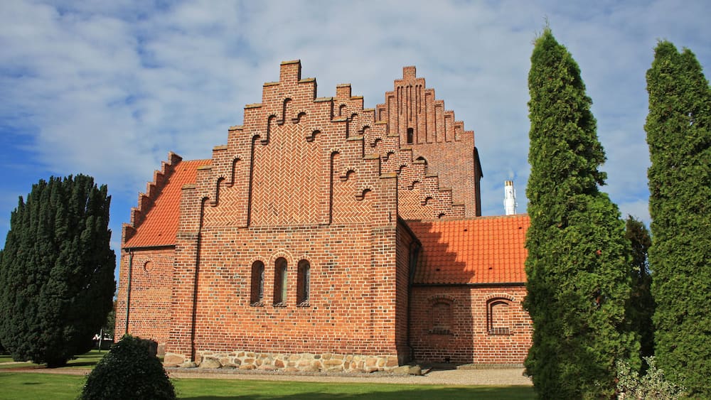 Ein großes Backsteingebäude mit rotem Ziegeldach und Rundbogenfenstern.