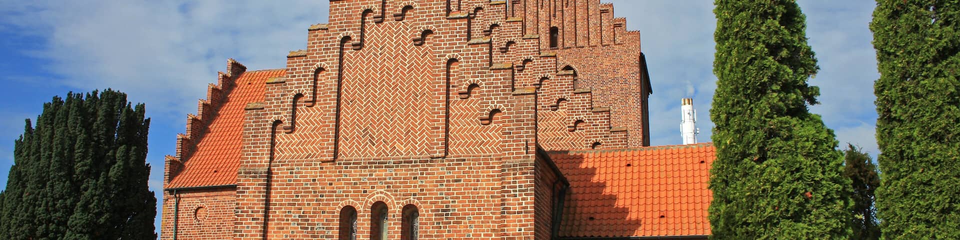 A large brick building with a red-tiled roof and arched windows.