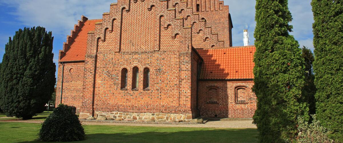 A large brick building with a red-tiled roof and arched windows.
