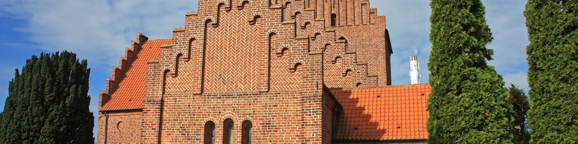 A large brick building with a red-tiled roof and arched windows.