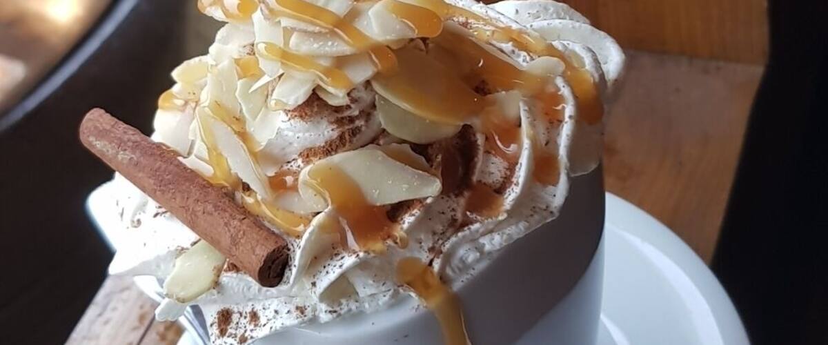 A dessert in a white cup with a spoon on a saucer.