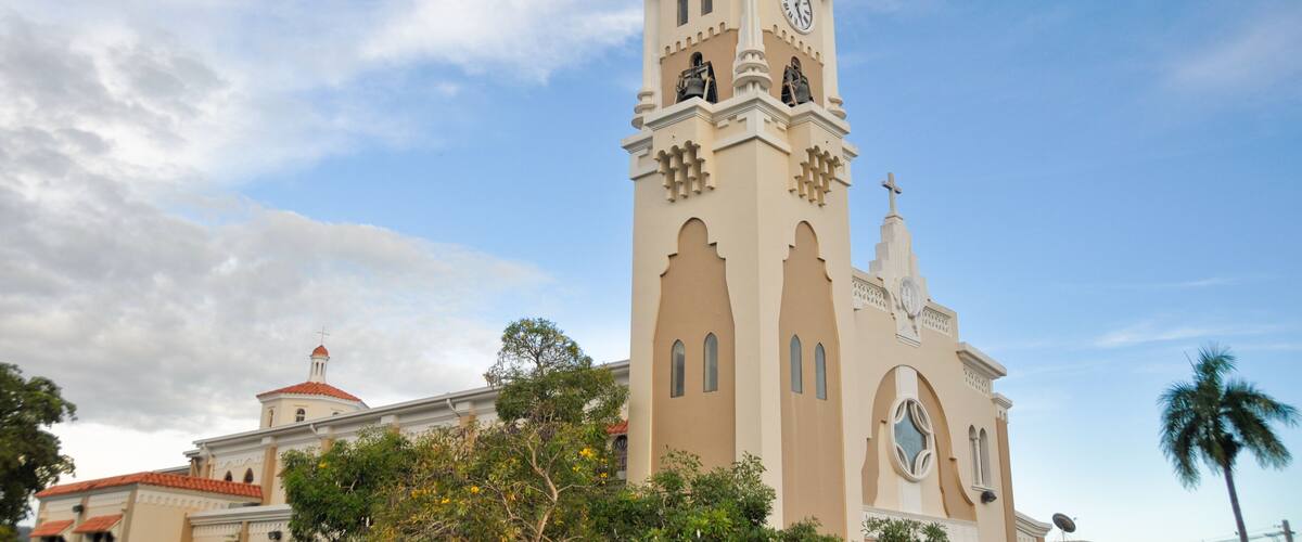 A church with a clock tower, surrounded by trees and a clear sky.