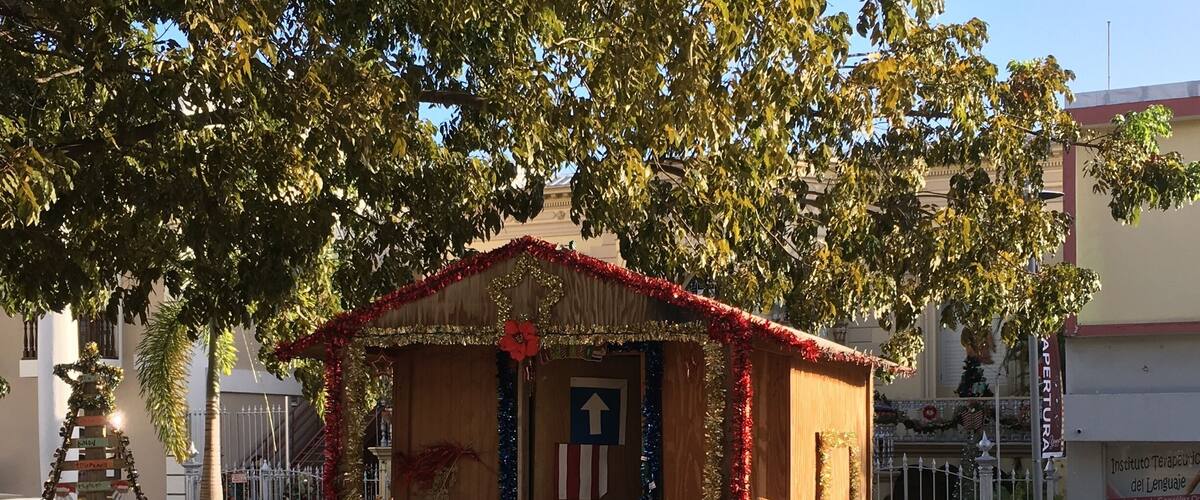 A small wooden kiosk decorated with festive garlands and ornaments, with a sign indicating an upward direction.