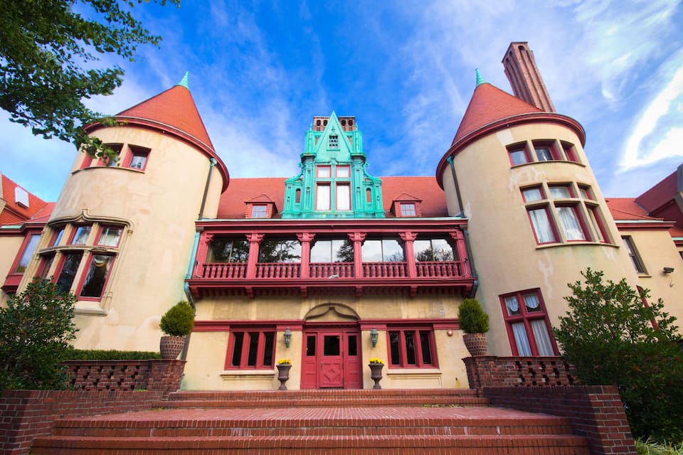 A historic building with a red and green facade, two towers, and a central turret.