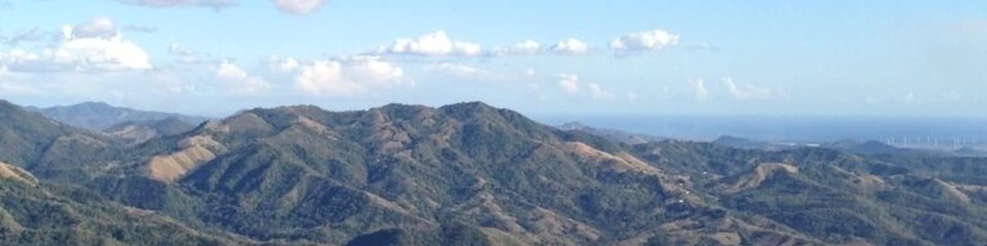 A mountainous landscape with rolling hills and scattered clouds.