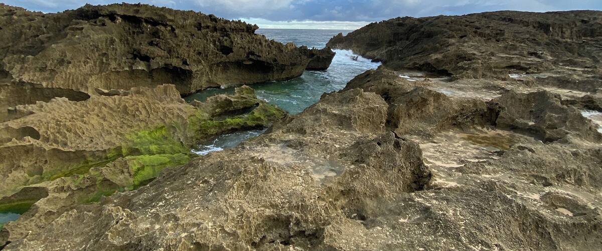 A rugged coastal landscape with rocky formations and a narrow water channel.