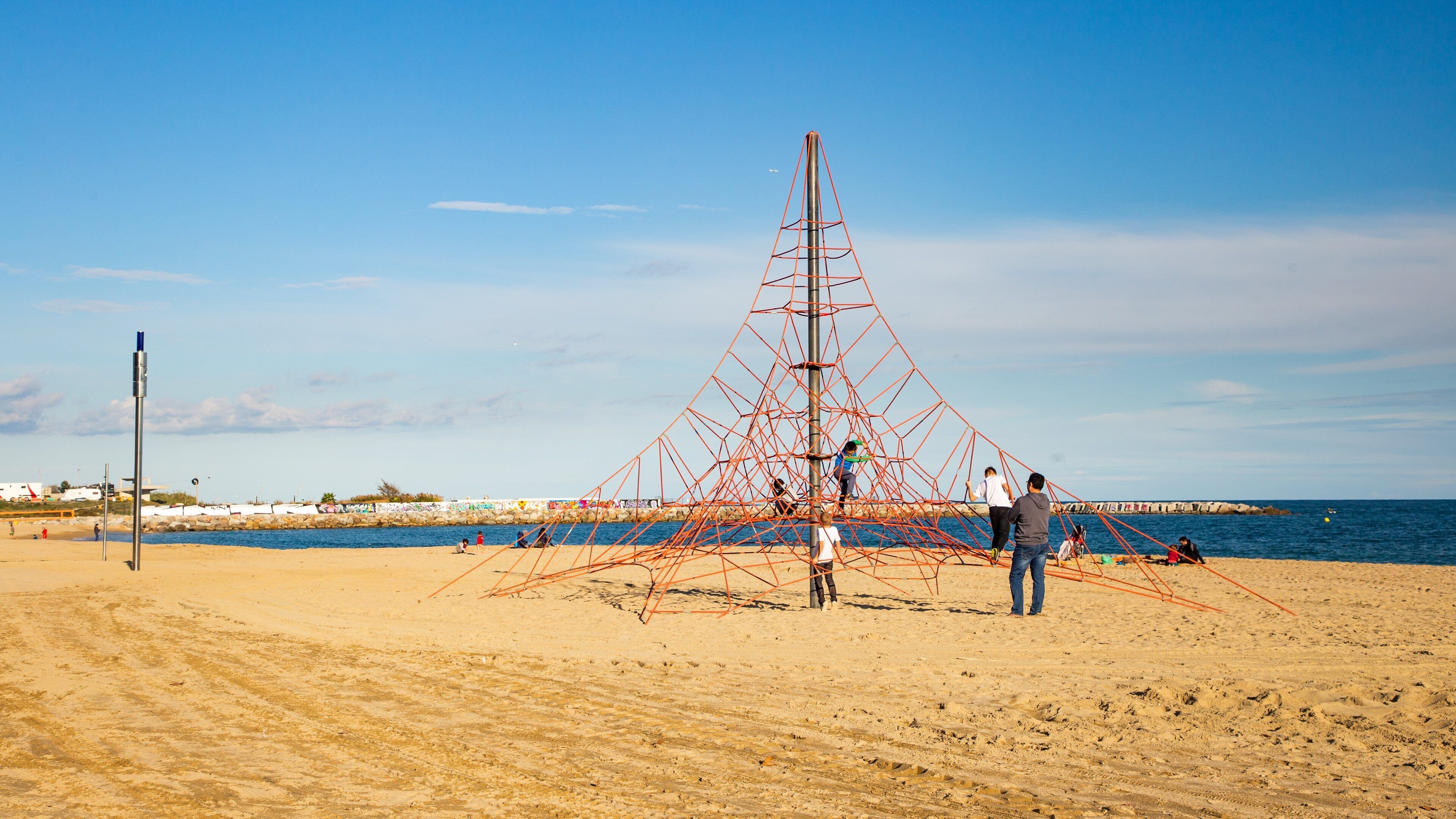 Mar Bella Beach featuring a playground and a sandy beach as well as a family